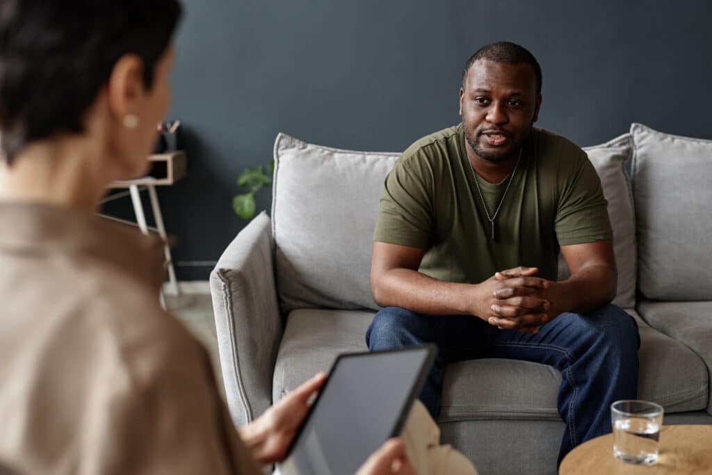 Portrait of African American adult man as army veteran sharing struggles with mental health therapist in session