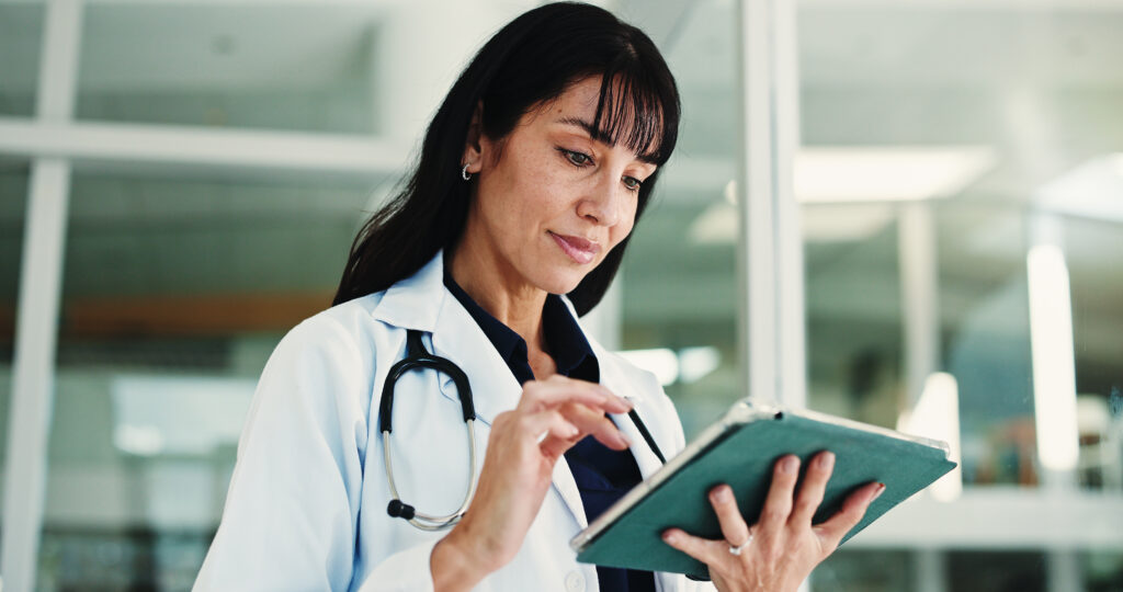 Woman, doctor and reading with tablet in hospital for research, medical report and confirm surgery. Surgeon, digital and browsing website for Telehealth, healthcare results and treatment information.