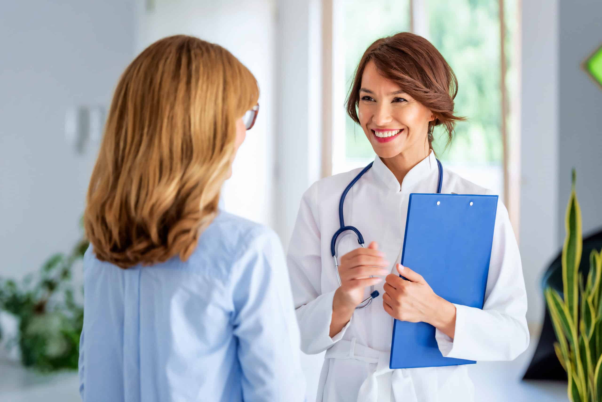 Female doctor consulting her patient while while she is explaining her symptoms standing in doctor's.